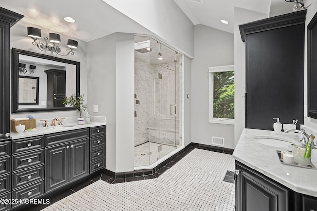bathroom featuring a stall shower, two vanities, baseboards, a chandelier, and lofted ceiling