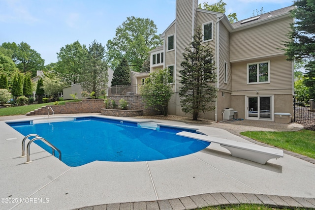 swimming pool featuring a patio area, a diving board, and fence