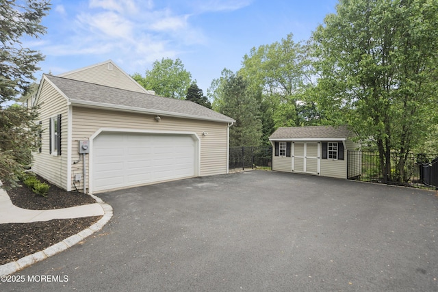 garage with asphalt driveway and fence