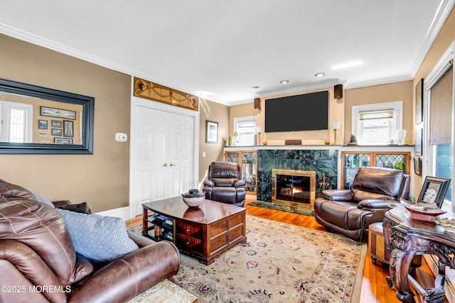 living room with wood finished floors, crown molding, a high end fireplace, and recessed lighting