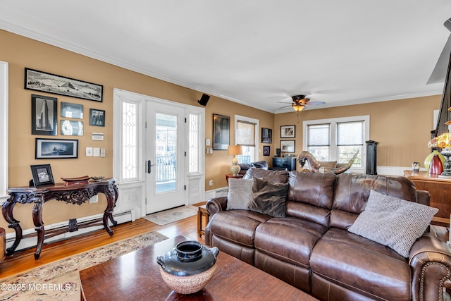 living area featuring wood finished floors, ceiling fan, crown molding, baseboard heating, and a baseboard radiator