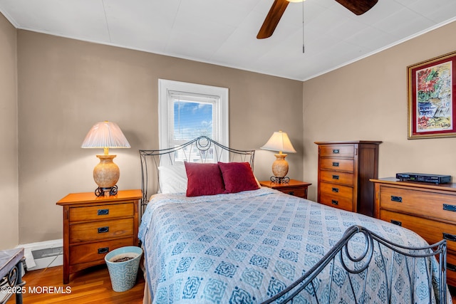bedroom with wood finished floors, ornamental molding, a ceiling fan, and baseboards
