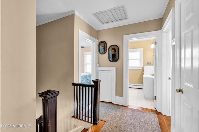 hall featuring an upstairs landing, wood finished floors, plenty of natural light, baseboard heating, and crown molding