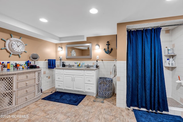 bathroom featuring tile walls, a tile shower, vanity, a wainscoted wall, and recessed lighting