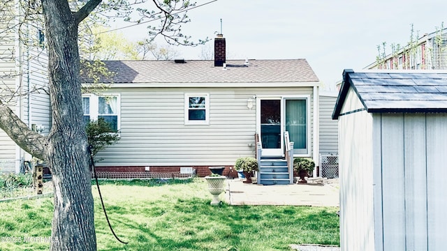 back of house featuring entry steps, a chimney, a lawn, and a patio