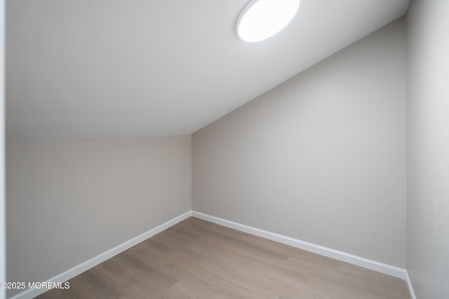 bonus room featuring lofted ceiling, light wood-type flooring, and baseboards