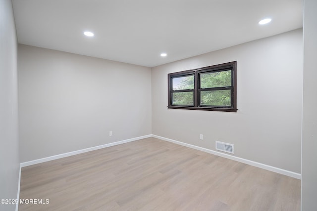 empty room with light wood-style floors, recessed lighting, and baseboards