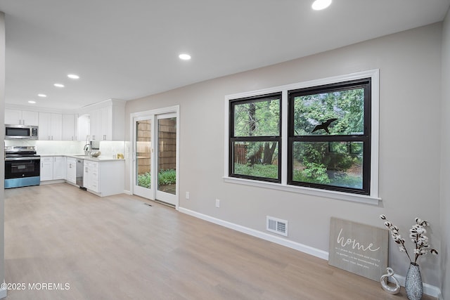 kitchen featuring stainless steel appliances, light wood finished floors, recessed lighting, baseboards, and light countertops
