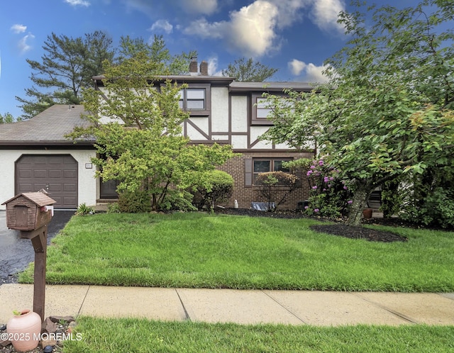 view of front facade with stucco siding, a front yard, a garage, brick siding, and a chimney