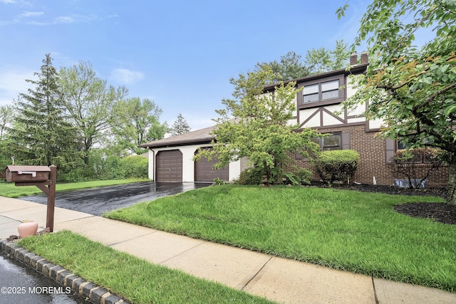 view of front of property with driveway, a front lawn, an attached garage, stucco siding, and a chimney