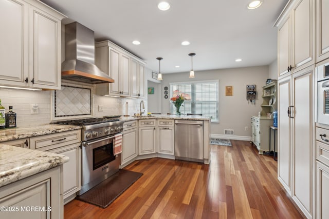 251 Worth St, Brick, NJ 08724 - kitchen featuring stainless steel appliances, wall chimney exhaust hood, a peninsula, a sink, and backsplash