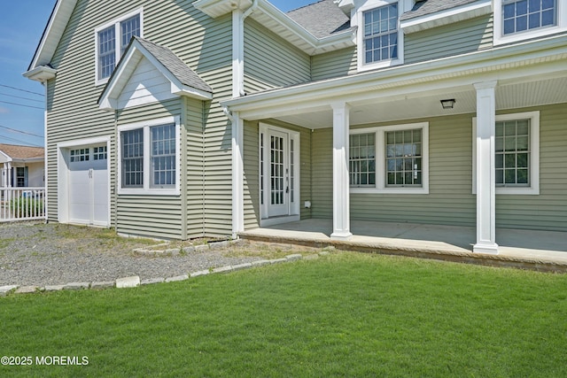 view of side of property with a garage, a porch, a shingled roof, a lawn, and driveway