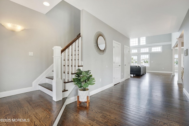 foyer featuring wood finished floors, stairs, and baseboards