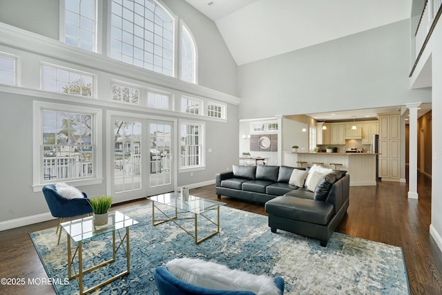 living room featuring high vaulted ceiling, baseboards, plenty of natural light, and dark wood finished floors