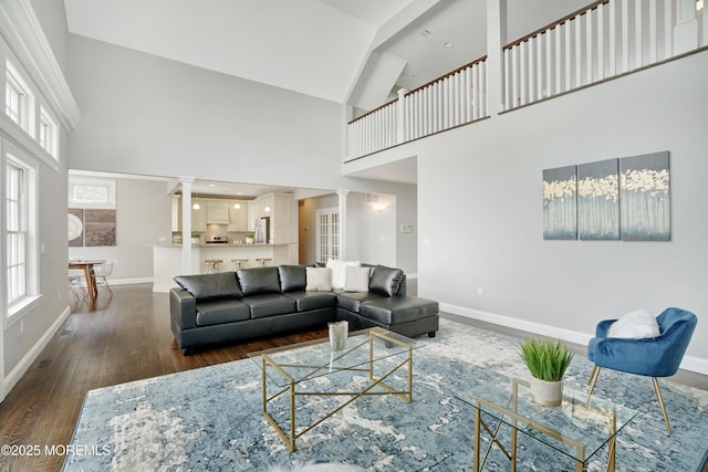living room featuring baseboards, high vaulted ceiling, wood finished floors, and healthy amount of natural light