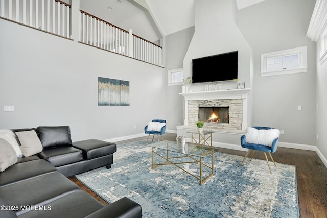 living room featuring wood finished floors, high vaulted ceiling, a fireplace, and baseboards