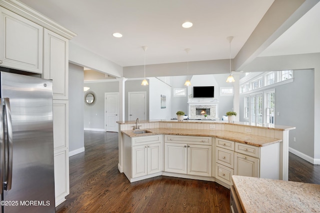 kitchen with freestanding refrigerator, a sink, baseboards, a lit fireplace, and open floor plan
