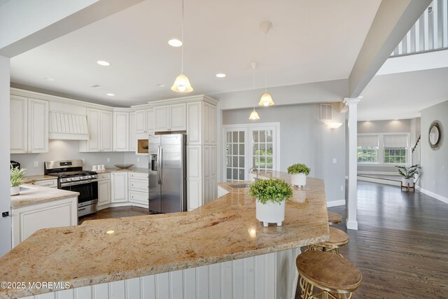kitchen featuring appliances with stainless steel finishes, light stone countertops, a sink, dark wood-type flooring, and baseboards