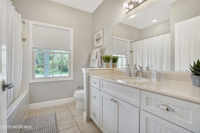 bathroom with toilet, vanity, baseboards, tile patterned floors, and shower / tub combo