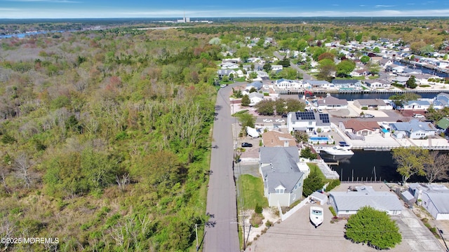 aerial perspective of suburban area featuring a nearby body of water and a heavily wooded area