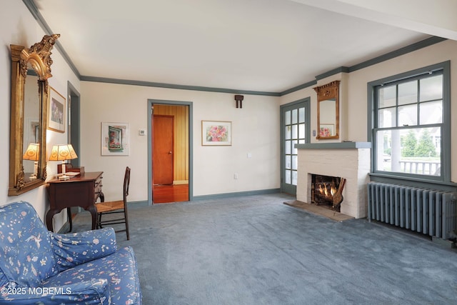 living room featuring radiator, ornamental molding, carpet flooring, a brick fireplace, and baseboards