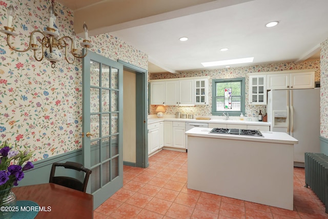 kitchen with white fridge with ice dispenser, stainless steel gas stovetop, white cabinets, light countertops, and wallpapered walls