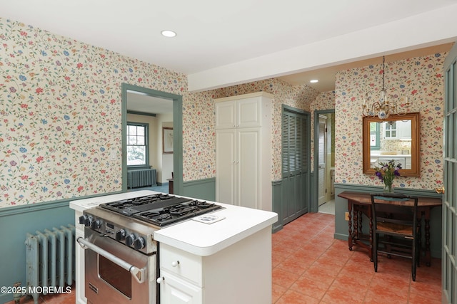 kitchen with wallpapered walls, high end range, radiator, a wainscoted wall, and light countertops