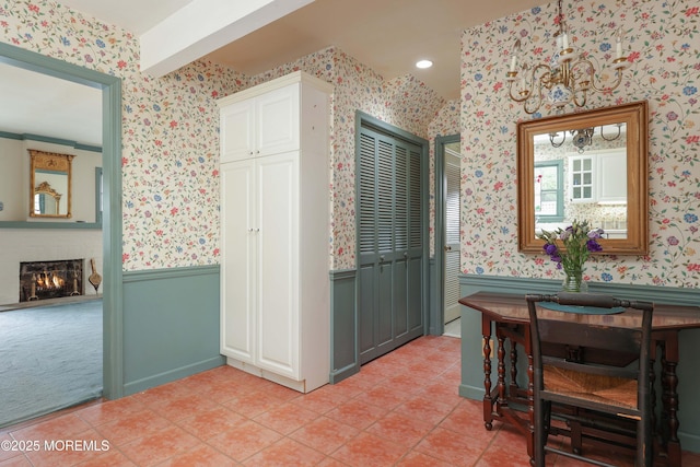 dining space featuring wallpapered walls, a wainscoted wall, light tile patterned floors, and a warm lit fireplace