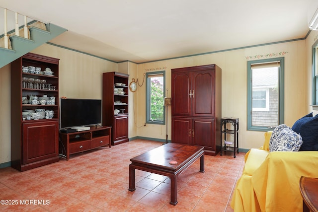 living area with light tile patterned flooring, healthy amount of natural light, baseboards, and crown molding