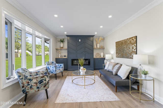 living area featuring crown molding, baseboards, recessed lighting, a large fireplace, and light wood-style flooring