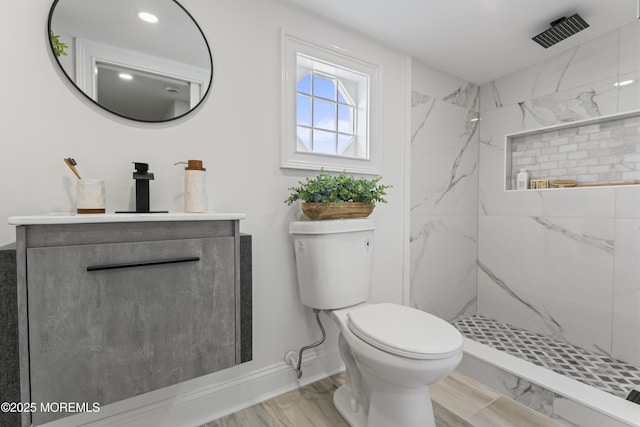 bathroom featuring toilet, vanity, a marble finish shower, and baseboards