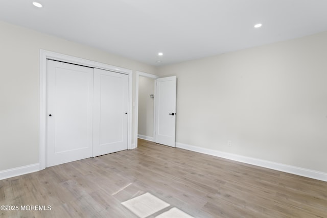 unfurnished bedroom featuring recessed lighting, light wood finished floors, baseboards, and a closet