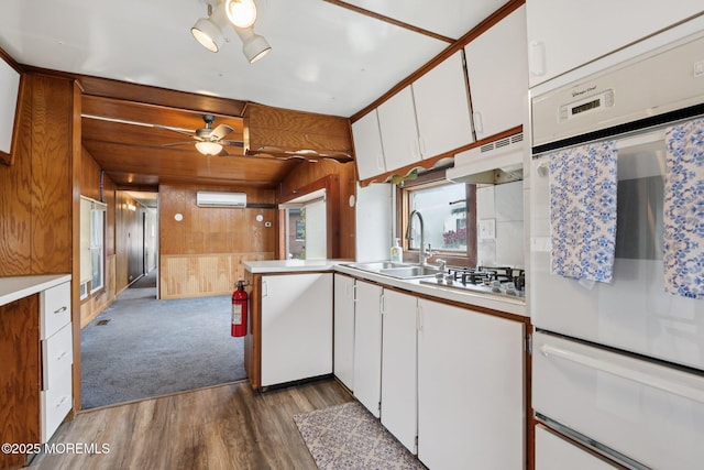 220 W Sylvania Ave Unit 16, Neptune City, NJ 07753 - kitchen featuring white oven, under cabinet range hood, wood finished floors, wood walls, and light countertops