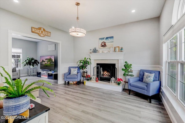 living room with plenty of natural light, a high end fireplace, light wood finished floors, recessed lighting, and wainscoting
