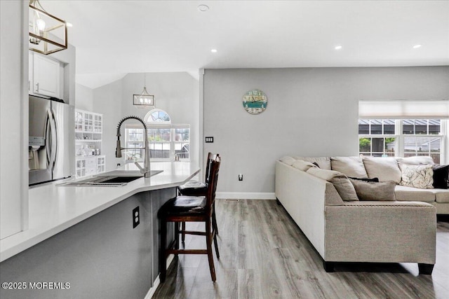 living room with light wood-type flooring, a chandelier, baseboards, and recessed lighting