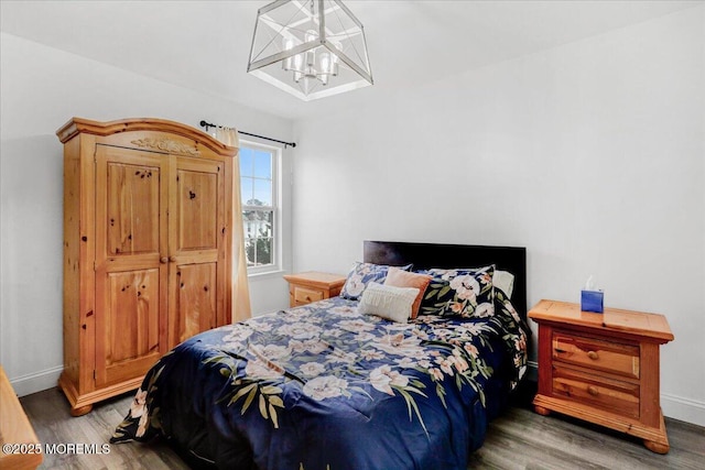 bedroom with wood finished floors, a chandelier, and baseboards