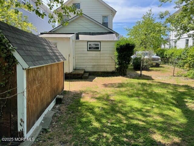 rear view of property featuring a storage unit and an outdoor structure