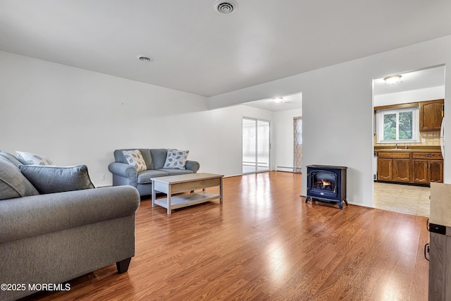 32 Bugle Ct, Toms River, NJ 08757 - living area featuring a wood stove, light wood-style floors, and a baseboard radiator