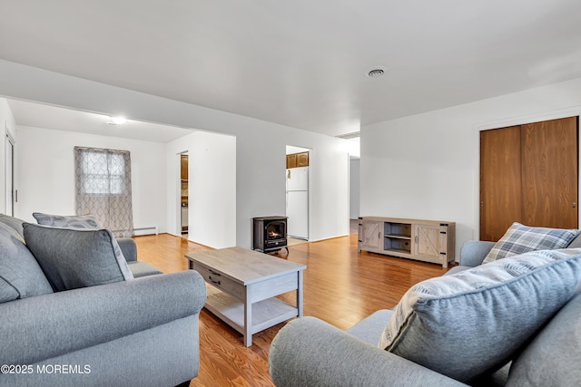 32 Bugle Ct, Toms River, NJ 08757 - living room featuring a wood stove, a baseboard radiator, and light wood-style flooring