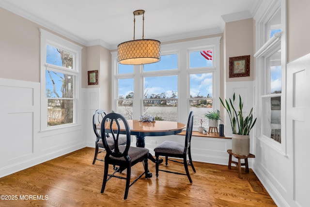 3 Sunset Dr, Asbury Park, NJ 07712 - dining area featuring a decorative wall, crown molding, a water view, wainscoting, and light wood finished floors