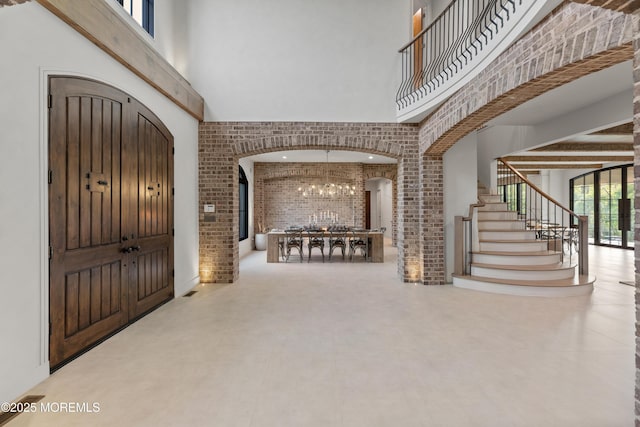 1 Preakness Way, Colts Neck, NJ 07722 - entrance foyer featuring a high ceiling, brick wall, arched walkways, stairs, and a chandelier