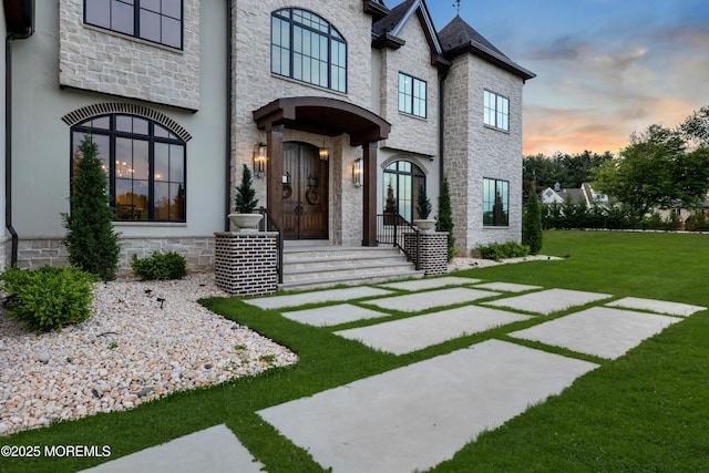 1 Preakness Way, Colts Neck, NJ 07722 - exterior entry at dusk featuring stone siding and a lawn