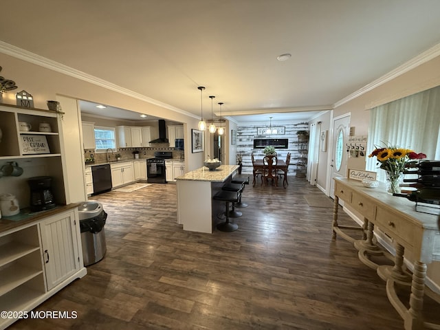 kitchen with black appliances, wall chimney exhaust hood, ornamental molding, a kitchen island, and a breakfast bar