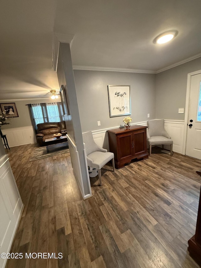 entrance foyer with ornamental molding, dark wood finished floors, a wainscoted wall, a decorative wall, and a ceiling fan