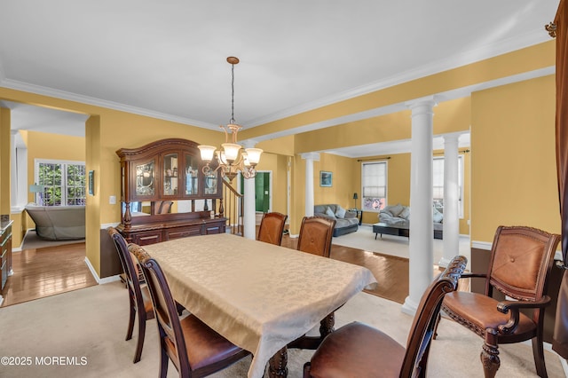 dining room featuring ornate columns, crown molding, a chandelier, and baseboards
