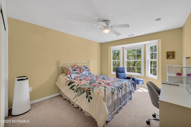 bedroom featuring light colored carpet, baseboards, and a ceiling fan
