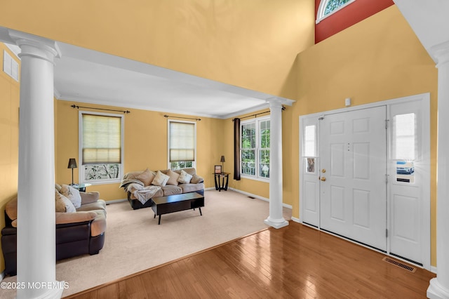 foyer entrance featuring decorative columns, hardwood / wood-style flooring, baseboards, crown molding, and a high ceiling