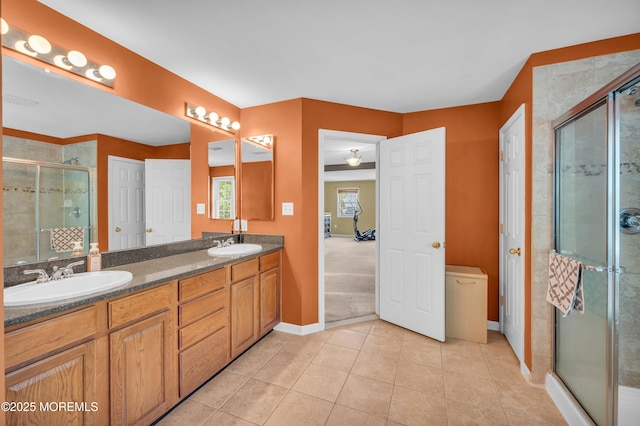 full bathroom with a shower stall, double vanity, tile patterned floors, and baseboards