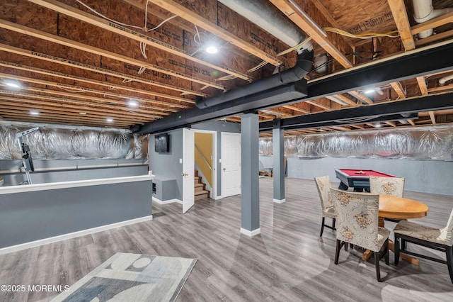 finished below grade area featuring stairs, baseboards, and wood finished floors