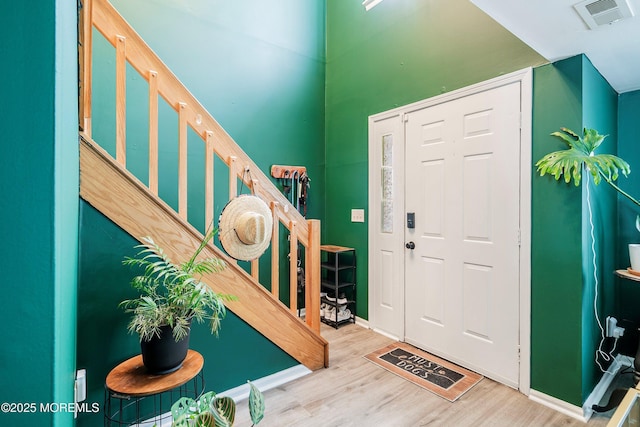 entryway featuring wood finished floors, baseboards, and stairs